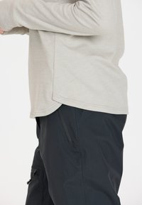 Lichtgrijze langemouwen top met een ronde zoom, gecombineerd met strakke zwarte broek met een zijzak en een gestroomlijnd ontwerp.