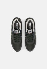 Dark green athletic shoes with gray accents, textured surfaces, and black laces. Features padded lining and visible branding on the tongue.