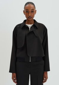 Zwarte cropped jas met een notch-kraag, een rits aan de voorkant en een knoopflapdetail. Kenmerkt een textuurstof en een geribde zoom.