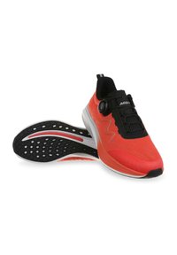 MBT running shoes featuring a bright red fabric upper, black accents, a textured sole with a unique pattern, and a dial for adjustable fitting.