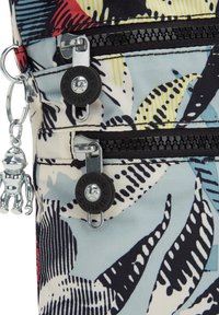 Kuvioitu kangaspussi, jossa on kaksi mustaa vetoketjua, hopeinen varustus ja apinakynttiläkoriste. Ominaisuudet sinisiä, mustia ja punaisia lehtimuotoja.