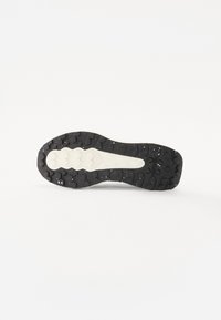 Semelle en caoutchouc noir avec un motif de crantage texturé et une semelle intermédiaire en caoutchouc blanc. Présente des rainures de traction pour une meilleure adhérence. Design épuré et minimaliste.