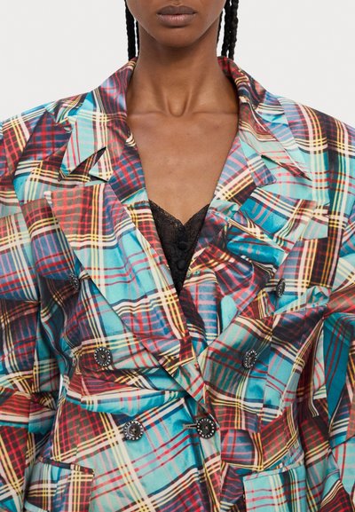 Americana de doble botonadura colorida en un vibrante patrón de cuadros que presenta rojo, azul y negro. Tejido suave con grandes botones y cuello de solapa.