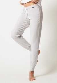 Lichtgrijze joggers met een zachte, gestructureerde stof, voorzien van een verstelbare trekkoordbundel en taps toelopende boorden bij de enkels.