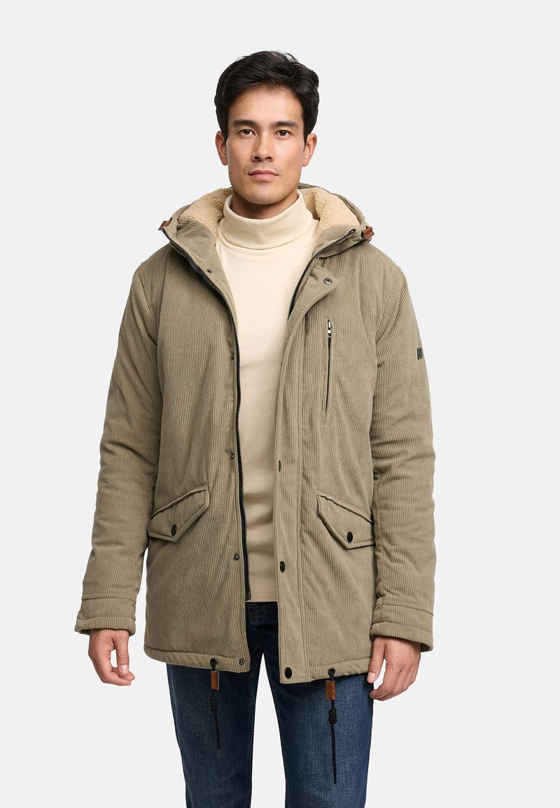 Grüne Cordjacke mit einer fellgefütterten Kapuze, Reißverschluss vorne und zwei Fronttaschen. Verfügt über Kordelzüge am Saum und braune Lederdetails.