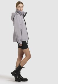 Light purple waterproof jacket with hood, black accents, front zipper, and two side pockets, paired with black shorts and tall black boots.