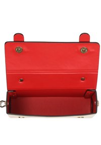 Zwarte en crèmekleurige handtas met een rode binnenkant. Voorzien van een magnetische sluiting en decoratieve gouden hardware. Soepele leren textuur, rechthoekige vorm.