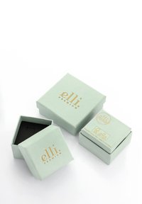 Une boîte-cadeau en carton vert clair avec un intérieur noir, ornée du texte doré "elli. PREMIUM" sur le dessus, et une autre petite boîte à côté.