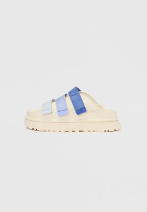 Sandaler med en kremfarget yttersåle og tre justerbare stropper i lyseblått og mørkeblått. Designet har en kraftig, teksturert såle.