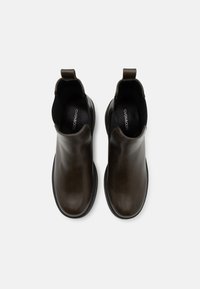 Bottes ankle en cuir marron au design élégant, côtés élastiques et une boucle pour un enfilage facile. Texture lisse avec un bout arrondi.