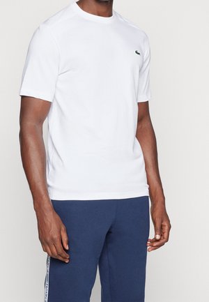 Witte katoenen t-shirt met korte mouwen, met een groen Lacoste-logo op de linkerborst. Glad textuur, ronde halslijn, klassieke pasvorm.