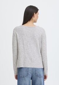 Maglione grigio lavorato a maglia con dettagli di perle sulle maniche, scollo tondo e vestibilità comoda, abbinato a jeans di denim blu.