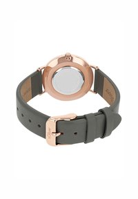 Roségoldfarbene Uhr mit rundem Gehäuse, grauem Lederarmband und Metallverschluss. Die Rückseite hat eine polierte silberne Fläche mit Markierungen.