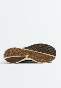 Semelle de chaussure avec motif de bande de roulement en caoutchouc marron et brun foncé conçu pour l'adhérence et la stabilité sur les surfaces planes.
