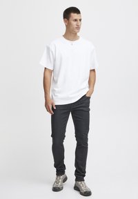 Vit bomulls t-shirt med rund hals, kombinerad med mörk denimjeans. Skorna har grå och svarta accenter och visar en sportig design.