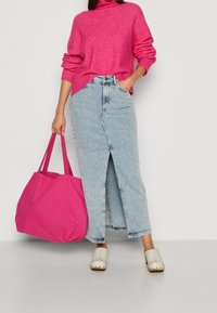 Fuchsie pletený rolák, světlomodrá maxi sukně z denimu s předním rozparkem, krémové dřeváky a velká růžová taška.