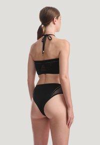 Svart bikini-set med en bandeau-topp med ett texturerat mönster och justerbart knyt, tillsammans med högmidjade underdelar med mesh-accenter.