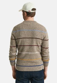 Beige Pullover mit mehrfarbigen horizontalen Streifen in Rot, Blau, Gelb und Weiß. Strickstruktur und gerippte Bündchen sowie Saum.