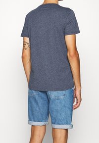 Námořnická modrá, tričko s krátkým rukávem a kulatým výstřihem, spárované s světle modrými denimovými šortkami s ohrnutými lemy a volným střihem.