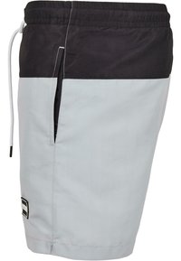 Shorts de bain en gris clair et noir, dotés d'une taille élastique, d'une fermeture à cordon, d'une poche latérale et d'un design à panneaux contrastants.