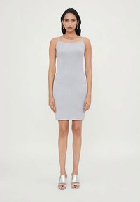 Hellgraues, geripptes Kleid mit Spaghetti-Trägern, figurbetontem Schnitt und knielanger Länge, kombiniert mit silbernen, hochhackigen Sandalen. Glatte Textur.