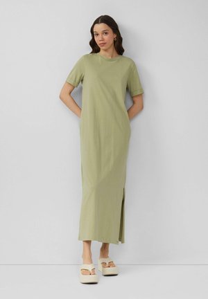 Olive green, short-sleeve, maxi dress with side slits, made of soft fabric. Worn with beige platform sandals. Simple, relaxed design.