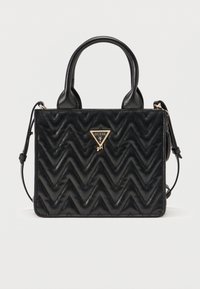 Μαύρη καπιτονέ τσάντα χειρός με ζιγκ-ζαγκ σχέδια, δύο λαβές, αποσπώμενο λουράκι ώμου και χρυσό λογότυπο Guess Girl στο κέντρο μπροστά.