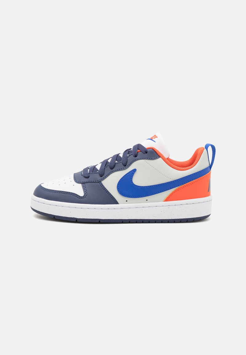 Nike sneakers featuring a white leather toe, grey upper, blue Swoosh logo, and orange accents on the heel and lining. Textured laces.