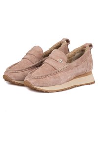 Zapatillas de ante rosa claro, tipo slip-on, con forro de piel de piel, punta redondeada, costuras decorativas y un pequeño emblema de loto plateado. Suela de goma para mayor agarre.