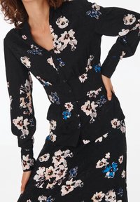 Black floral blouse featuring long sleeves, a button-down front, and a fitted waist. Floral pattern includes pink and blue hues.