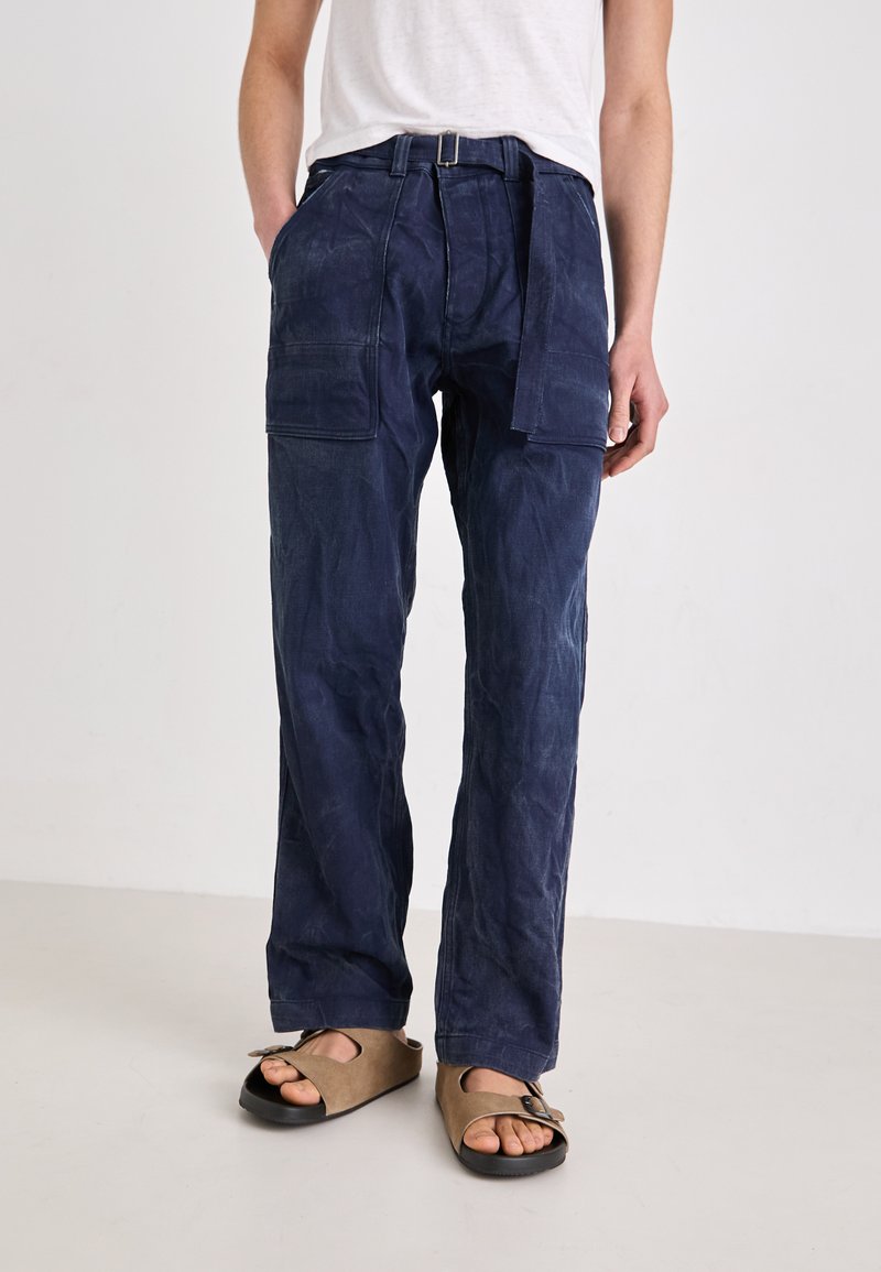 Marineblauwe cargobroek met een gestructureerde afwerking, voorzien van twee vo pockets, een riem met een zilveren gesp en een ontspannen pasvorm.