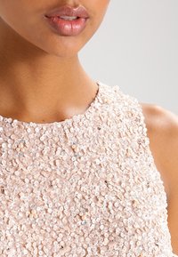 Beadtop aus weichem Pfirsichstoff, der dicht mit kleinen Pailletten bedeckt ist und mit Perlen und silbernen Akzenten verziert ist.