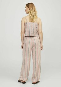 Strapless cropped top en wijde broek in een roze, grijze en witte gestreepte patroon. De stof lijkt lichtgewicht; heeft achterzakken.