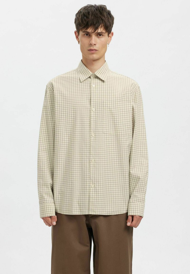 Helebeež toonides ruuduline särk nööpidega kaelusega, pika varrukaga ja ühe rinnataskuga. Pehme, kootud kangast tekstuur.