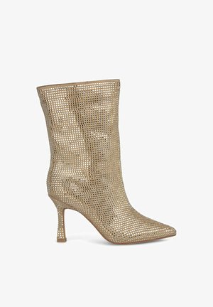 Goldene High-Heel-Ankle-Boots mit offenem Mesh-Design, spitzem Fuß und schlankem Stiletto-Absatz. Texturierte Oberfläche mit gleichmäßigen Perforationen.