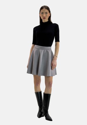 Top nero a maniche corte, gonna grigia a campana, stivali neri fino al ginocchio. Tessuto liscio, vestibilità su misura, design semplice e linee pulite.
