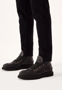 Botas de senderismo negras con una parte superior de cuero suave, ojales de metal y una puntera reforzada. Suela de goma para tracción y durabilidad.