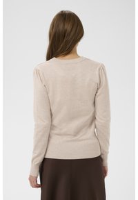 Svetlo bež pulover z okroglim izrezom, rebrastim spodnjim robom in manšetami ter nabranimi ramenimi šivi, izdelan iz mehkega, teksturiranega blaga.