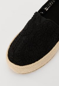 Čierne espadrilky s textúrovaným textilem a zložitým vzorom, elastickou stranou a prírodnou jútovou podrážkou. Dizajn s okrúhlou špičkou.