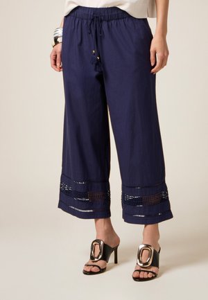 Navyblauwe wijde broek van lichtgewicht materiaal, met een trekkoord taille met kwastjes en decoratieve uitsneden aan de zoom.