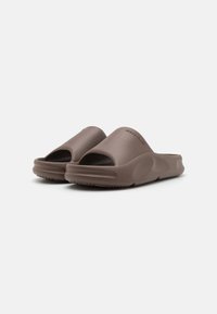 Brune, gummisandaletter med åben tå-design, teksturerede såler og en glat finish, med mærkets navn præget på siden.