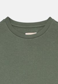 Ελιά πράσινο μπλουζάκι με στρογγυλή λαιμόκοψη και υφή στην επιφάνεια. Έχει κλασική εφαρμογή και μαλακό ύφασμα. Ετικέτα ορατή στο εσωτερικό του λαιμού.