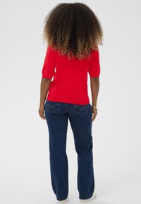 Rød kortærmet sweater med en tætsiddende stil, parret med mørkeblå lige ben jeans. Enkel design, blød tekstur, ingen synlige mønstre.