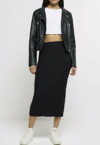 Czarna skórzana krótsza kurtka ze srebrnymi zamkami, zestawiona z czarną prążkowaną spódnicą midi. Całość uzupełniają białe sneakersy.