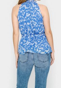 Modrý halter top s abstraktním vzorem, sepeplum pasem a texturovanou látkou. V kombinaci s lehkými denimovými džíny.