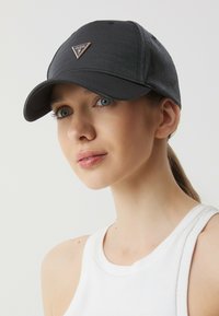 Czarna czapka z textured materiału z zakrzywionym daszkiem i złotym trójkątnym logo. Posiada klasyczny design i regulowany pasek z tyłu.