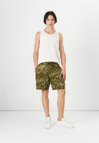 Hvid ribbet tanktop, olivengrønne shorts med hvidt blomstermønster, snørrebånd i taljen, og hvide sneakers. Enkle og afslappede tøj.