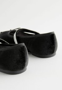 Schwarze Samt-Ballettschuhe mit einer weichen Textur, runder Spitze und flexibler Sohle. Verfügt über silberne Details an den Riemen für zusätzlichen Akzent.