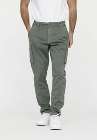 Olijfgroene cargobroek van katoen, met zijzakken, een knoopsluiting en een tapered fit, gecombineerd met witte sneakers.
