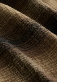 Bruine wolstof met een visgraat- en ruitpatroon, weergegeven in zachte plooien en gedetailleerde close-up textuur.